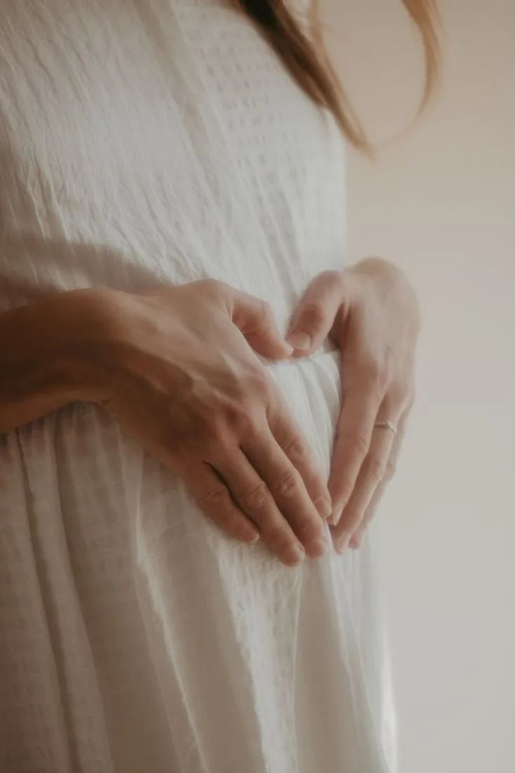Gestante formando um coração com as mãos sobre a barriga